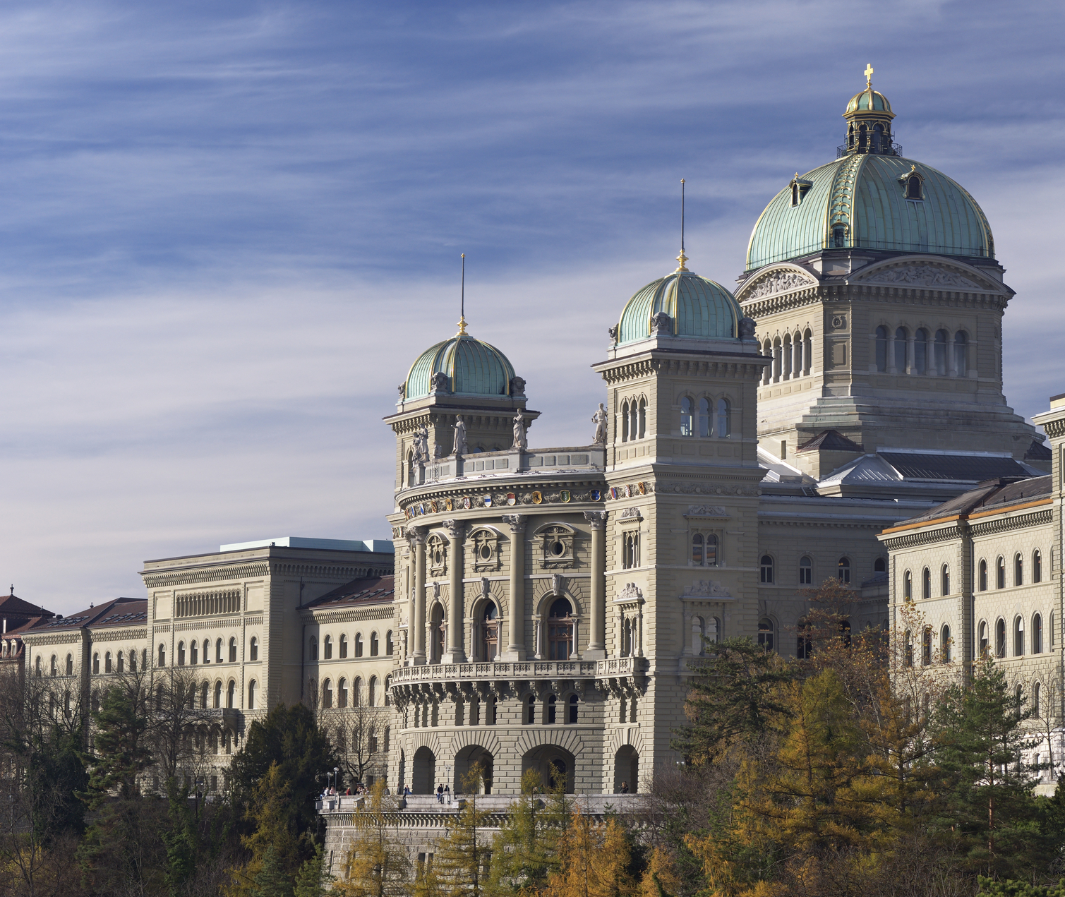 The Swiss house of parliaments (Bundeshaus). Side view shot in autumn with yellow trees in the foreground.