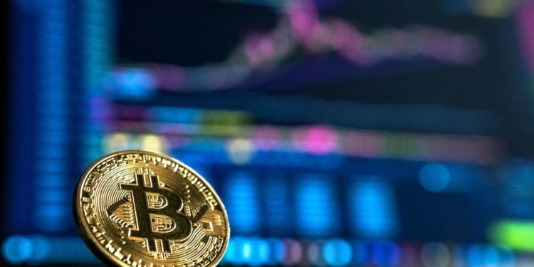 Un bitcoin delante de un tablero de análisis de mercado. Fuente: André François McKenzie/ Unsplash.com