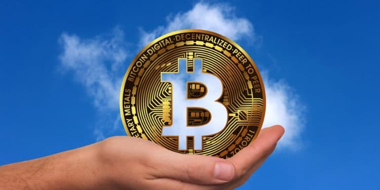 Bitcoin siendo alzado por una mano en un cielo despejado. Fuente: geralt/ Pixabay.com