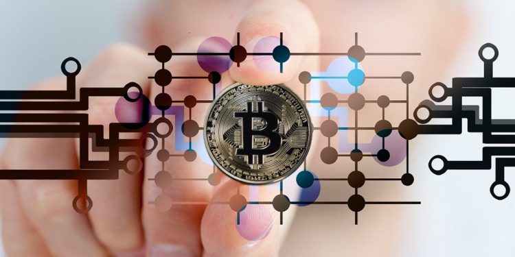 Mano de hombre con moneda bitcoin de plata. Fuente: Gerd Altmann/pixabay.com