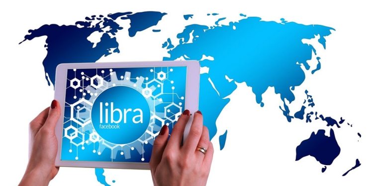 Tableta con alusión a Libra, de Facebook, sobre mapa del mundo. Fuente:  Gerd Altmann/pixabay.com
