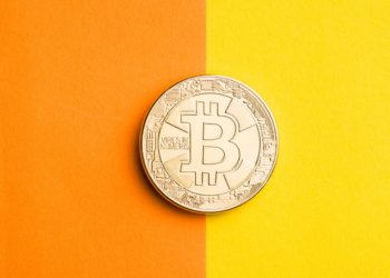 Un bitcoin posado en un papel bicolor. Fuente: jirkaejc/ Envato Elements.