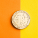 Un bitcoin posado en un papel bicolor. Fuente: jirkaejc/ Envato Elements.