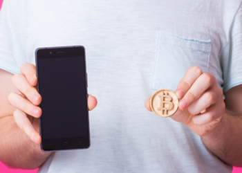 Un hombre enseña su bitcoin y teléfono celular. Fuente: Satura_/ Envato Elements.