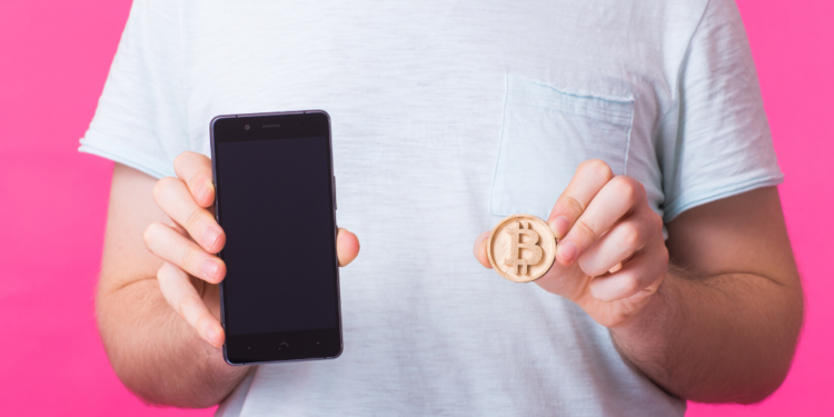 Un hombre enseña su bitcoin y teléfono celular. Fuente: Satura_/ Envato Elements.