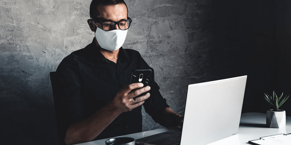 Un hombre trabaja con mascarilla para protegerse del coronavirus. Fuente: serbogachuk/ Envato Elements.