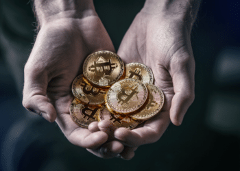 Una persona cargando un puño de monedas de bitcoins. Fuente: grafvision/ Envato Elements.