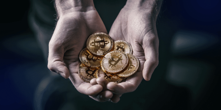 Una persona cargando un puño de monedas de bitcoins. Fuente: grafvision/ Envato Elements.