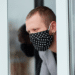 Un hombre mira por la ventana con mascarilla. Fuente: bondarillia/ Envato Elements.