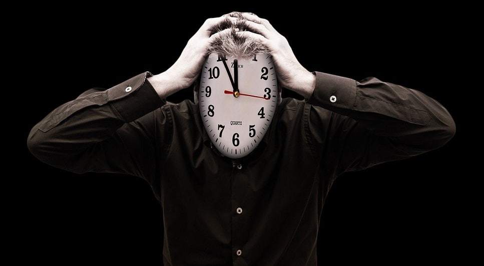 Hombre con cara de reloj sujetándose la cabeza con ambas manos. Fuente: Gerd Altmann / Pixabay