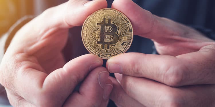 Hombre sosteniendo con ambas manos moneda de bitcoin. Fuente: stevanovicigor /   elements.envato.com