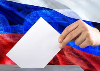 Mano votando con un fondo de bandera de Rusia sobrepuesto con cadena blockchain. Composición por CriptoNoticias erika8213 / elements.envato.com ; iLexx /  elements.envato.com ;  jorono /  pixabay.com