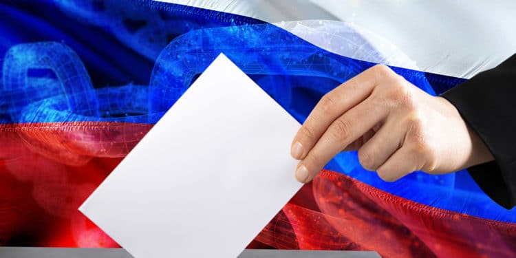 Mano votando con un fondo de bandera de Rusia sobrepuesto con cadena blockchain. Composición por CriptoNoticias erika8213 / elements.envato.com ; iLexx /  elements.envato.com ;  jorono /  pixabay.com