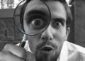 Una persona con una lupa observando algo detalladamente.