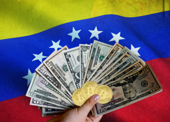 Mano sosteniendo billetes de dólares y monedas de Bitcoin con bandera de Venezuela en el fondo. Composición por CriptoNoticias. jirkaejc / elements.envato.com; twenty20photos / elements.envato.com; Wirestock / Freepik.com