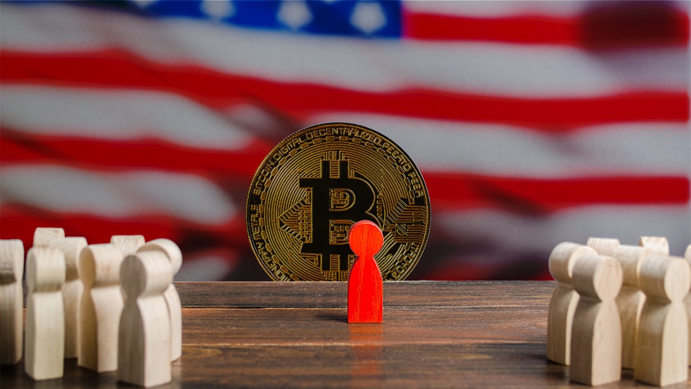 Figura de usuario discriminado con moneda de bitcoin frente a bandera de Estados Unidos de fondo. Composición por CriptoNoticias, jirkaejc / elements.envato.com; twenty20photos / elements.envato.com