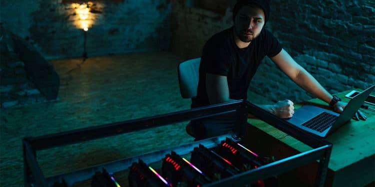 Hombre en la oscuridad con mineros de criptomonedas. Fuente: bernardbodo / elements.envato.com