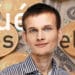 Vitalik Buterin frente a monedas de bitcoin sobre billetes de dólar. Composición por CriptoNoticias. bit2me / bit2me.com; leungchopan / elements.envato.com.