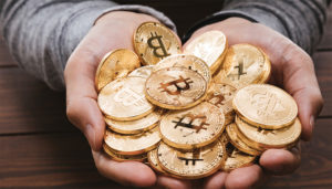 Dos manos sotienen un grupo de bitcoins físicos.