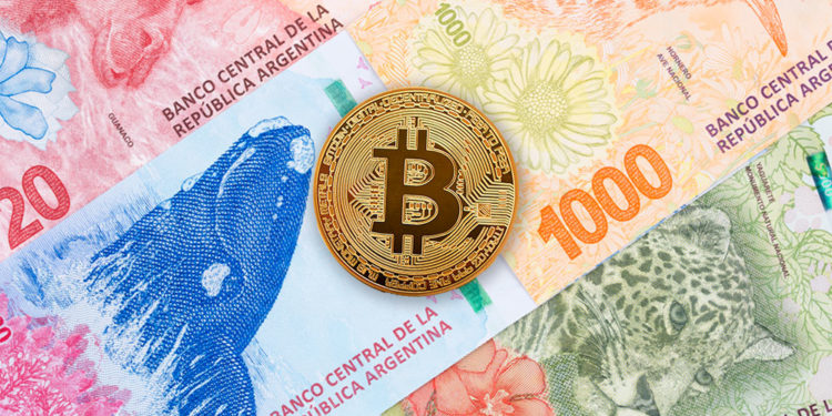 Moneda de Bitcon sobre billetes de pesos argentinos.