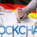 Mujer colocando sello en documento financiero con bandera de Alemania en el fondo y blockchain superpuesto. Composición por CriptoNoticias. martinholv / elements.envato.com; Pressmaster / elements.envato.com; rawpixel.com / freepik.com