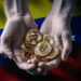 Manos sosteniendo monedas de Bitcoin con bandera de Venezuela en el fondo. Composición por CriptoNoticias. wirestock / freepik.com; grafvision / elements.envato.com