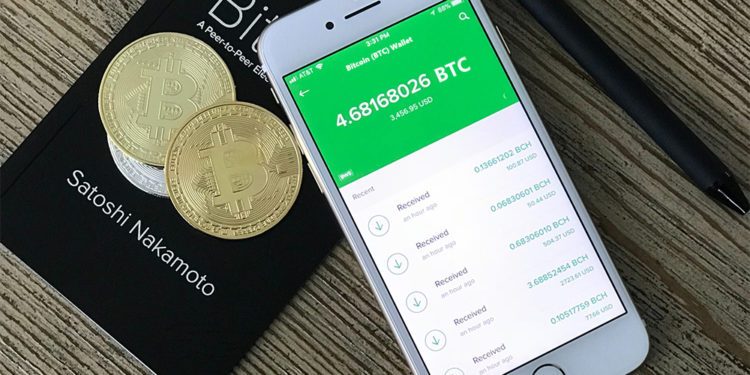 Saldo de bitcoin en teléfono junto a monedas de bitcoin sobre mesa. Fuente: David Shares / unsplash.com