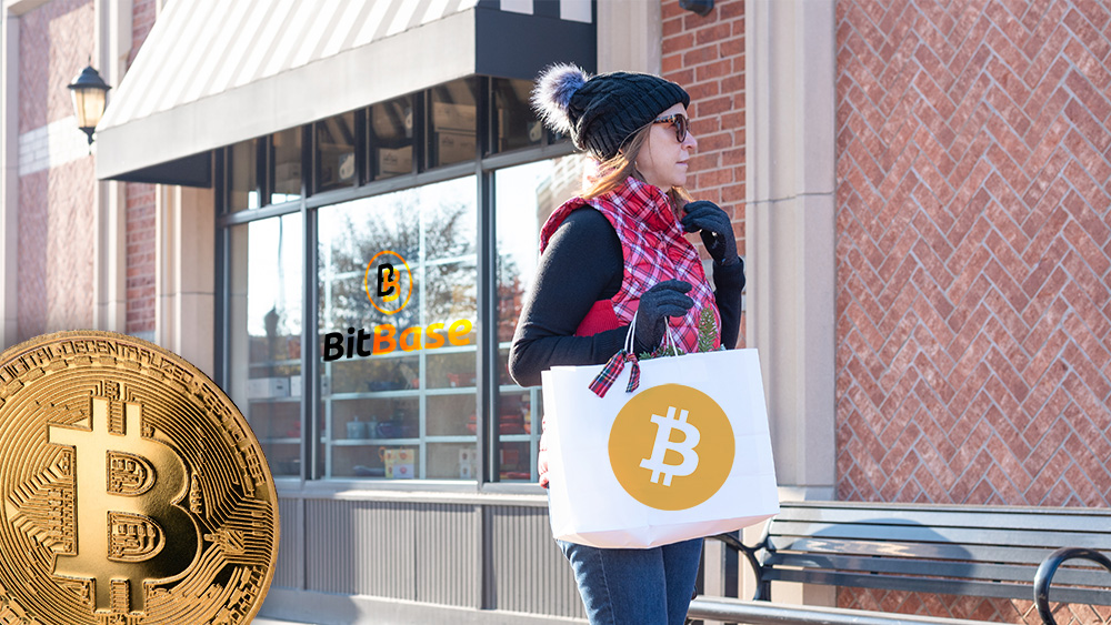 Mujer con bolsa de compras con logo de bitcoin con tienda de BitBase y moneda de Bitcoin en el fondo. Composición por CriptoNoticias. Bitcoin / bitcoin.org; LightFieldStudios / elements.envato.com; BitBase / bitbase.es; twenty20photos / elements.envato.com.