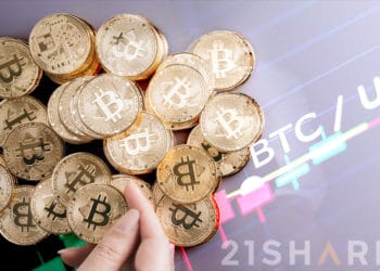 Mano sosteniendo moneda de Bitcoin con monedas de bitcoin apiladas sobre superficie con gráfico de precio con logo de 21Shares. Composición por CriptoNoticias. 21shares / 21shares.com; bitcointere / pxhere.com; avanti_photo / elements.envato.com.