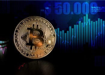 Moneda de Bitcoin con gráfico alcista del precio marcando USD 50.000 en el fondo