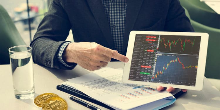 Hombre presentando gráficos de mercado en tablet con monedas de bitcoin sobre meda. Composición por CriptoNoticias. Sonyachny / elements.envato.com; sbqhw / piqsels.com; Rawpixel / elements.envato.com.