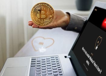 Escritorio con logo de Meduza y laptop con home de meduza.oi y mano sosteniendo bitcoin.