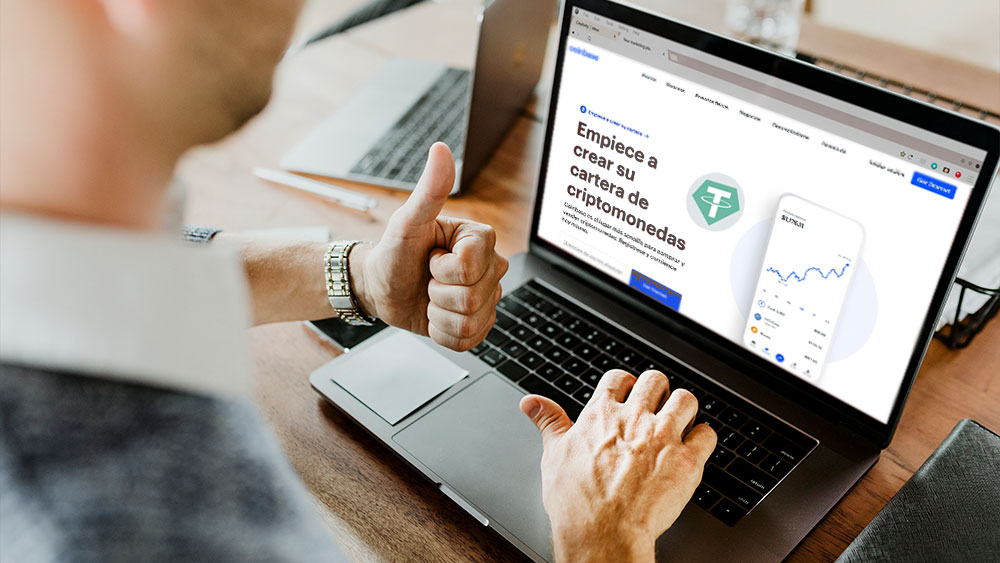 Hombre frente a laptop en sitio web de Coinbase con logo de Tether.