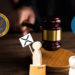 Mesa y maso de juez con logos de SEC y Ripple a los lados y protesta de personas de madera con cartel de XRP. Composición por CriptoNoticias Fuentes:   twenty20photos  /  elements.envato.com  ;  pngegg  /  pngegg.com  ;  cryptologos  /  ;