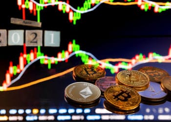 Gráfico bursátil con bitcoins y cubos de madera que denotan abril 2021.