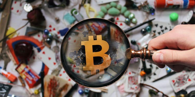Muchos objetos sobre mesa y lupa sobre bitcoin.
