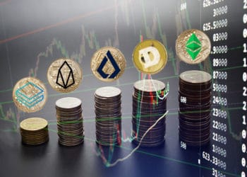 Pilas de monedas con logos de ethereum classic, dogecoin, lisk, eos, stratis con fondo de gráfico.