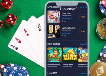 Mesa de juegos de casino, bitcon y ether, y teléfono inteligente con CLoudbet en pantalla.