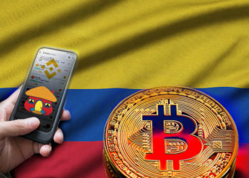 Bandera de Colombia y bitcoin, mano sosteniendo teléfono con app de Binance, su logo y logo de Davivienda.