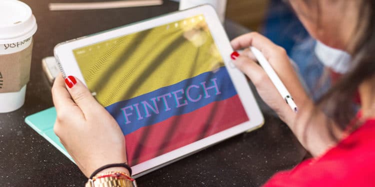 Mujer con tablet y bandera de colombia, con letras que dicen Fintech en la pantalla.