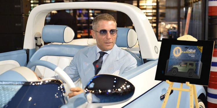 Lapo en su fiat con atril de NFT al lado.