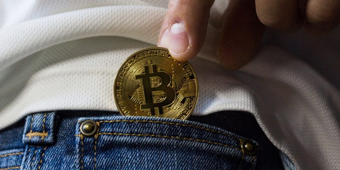 Metiendo en el bolsillo del pantalón un bitcoin