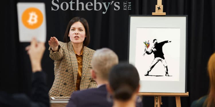 Subasta de obra de Banksy, persona ofertando en bitcoin y logo de Sotheby's al fondo.