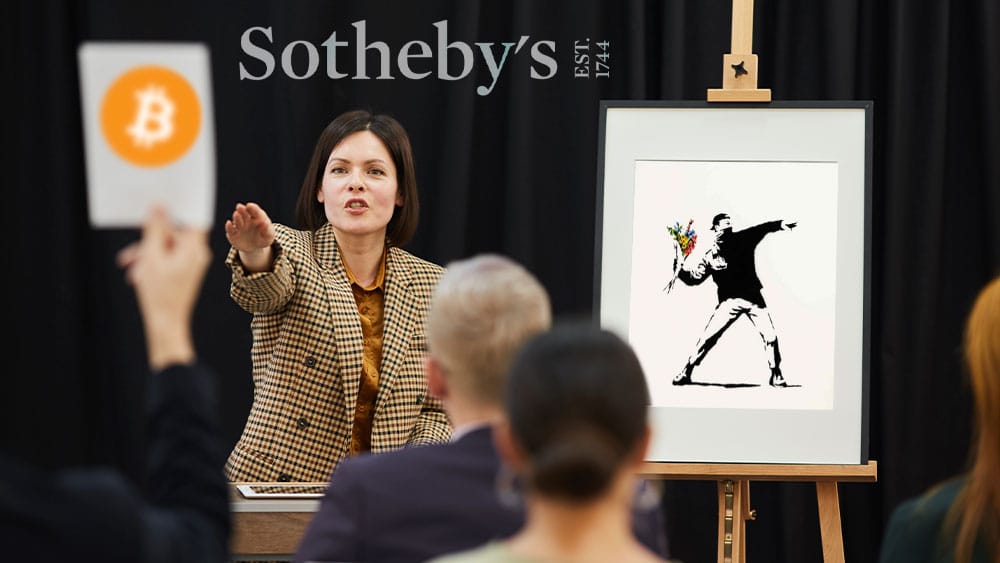 Subasta de obra de Banksy, persona ofertando en bitcoin y logo de Sotheby's al fondo.