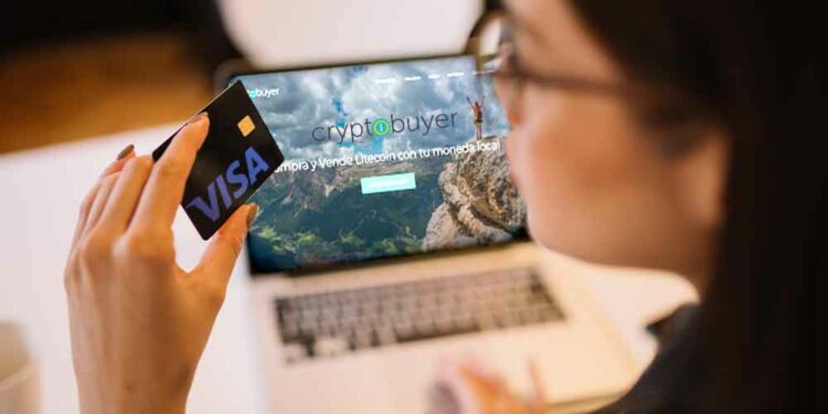 Tarjeta con logo de Visa y Bitcoin y pantalla con sitio web de Cryptobuyer.