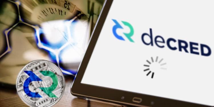 Tablet con logo de Decred y ícono de cargando al fondo red hexagonal, reloj y en la mesa criptomoneda de Decred.