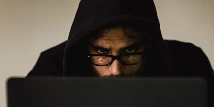 Hacker con logo de ethereum reflejado en los lentes.