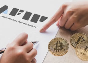 Planilla de AFIP y bitcoins sobre la mesa.