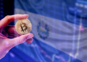 Pantalla con bandera de El Salvador y mano con bitcoin.