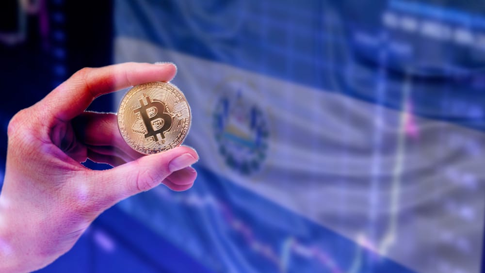 Pantalla con bandera de El Salvador y mano con bitcoin.